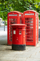 Obraz premium Red phone booths stand beside a postbox