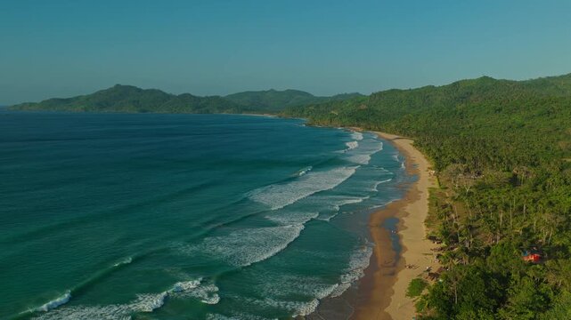 Aerial Left to Right Pan of Duli Beach Coastline in El Nido, Philippines. Drone Lateral Tracking Shot of Golden Sand Shoreline, Rolling Surf, and Blue Ocean.
