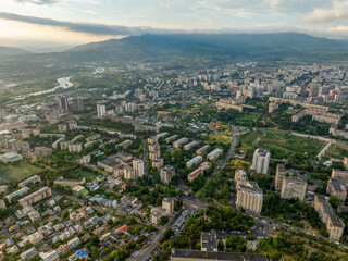 Fototapeta premium High-angle aerial drone panorama of large residential areas in Tbilisi, Georgia. The shot highlights dense Soviet-era concrete block apartments mixed with modern developments