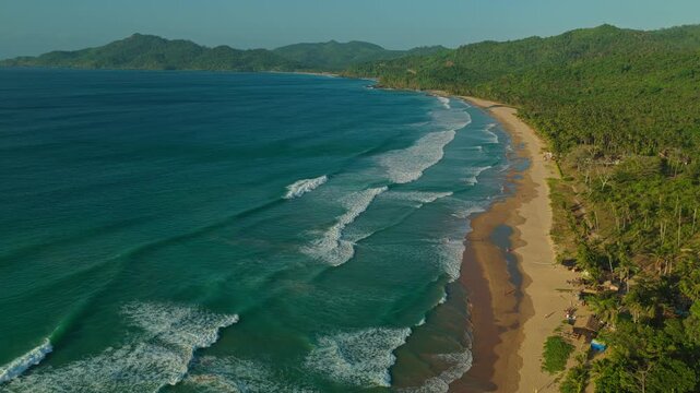 High Altitude Aerial Tracking Shot Over Waves at Duli Beach in El Nido, Philippines. Drone View of Rolling Ocean Surf, Breaking White Water, and Golden Sand Beach.