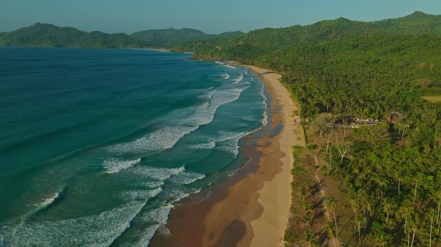 High Altitude Aerial Forward Tracking Shot Along Duli Beach Shoreline in El Nido, Philippines. Drone View of Golden Sand, Endless Rolling Ocean Surf, and Tropical Jungle.