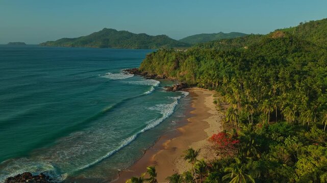 Aerial Backwards Reveal and Descent Over Duli Beach in El Nido, Philippines. Cinematic Drone Pull Away and Pedestal Down Shot Over Golden Sand Shoreline and Ocean Surf.