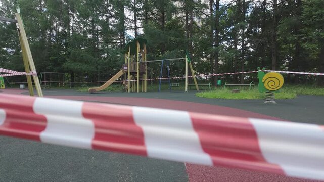 Wide view of empty playground surrounded by trees with restriction tape