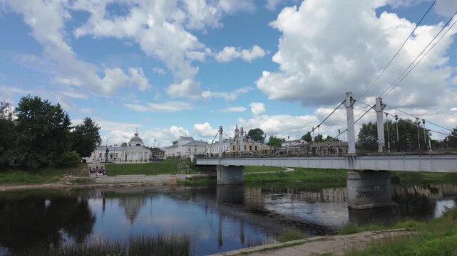 Pedestrian bridge over river with rotunda and historic townscape in Torzhok