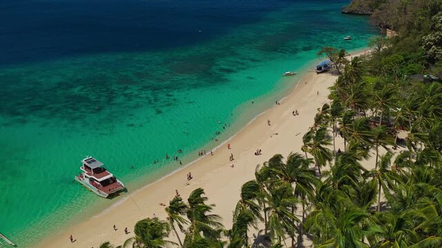 Aerial Flyover From Palm Trees to Ocean at Seven Commandos Beach in El Nido, Philippines. Drone Tracking Forward Over White Sand and Beautiful Turquoise Coral Reef.