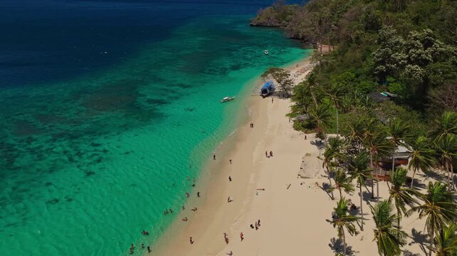Aerial Orbit of Seven Commandos Beach Shoreline in El Nido, Philippines. Cinematic Drone Curved Tracking Shot Over Clear Turquoise Ocean Reef and White Sand Beach.