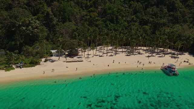 Aerial Orbit of Seven Commandos Beach with Gimbal Movement in El Nido, Philippines. Drone Flying Left to Right Over Turquoise Ocean, White Sand Shoreline, and Dense Jungle.