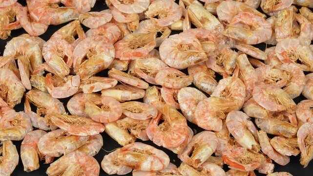 Full frame texture of many unpeeled dried shrimps rotating.