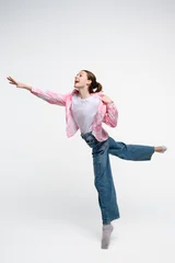 Happy teenage girl reaching forward while balancing on one leg. Studio portrait expressing freedom, aspiration, movement, optimism and playful energy. © o_lypa