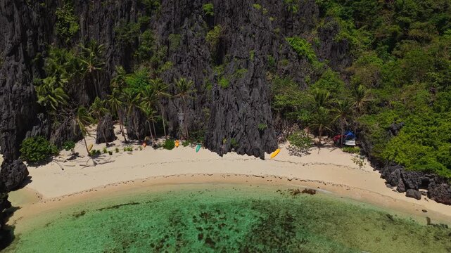 Aerial Forward Shot of Isolated Beach Near Secret Lagoon in El Nido, Philippines. Cinematic Drone Flying Towards White Sand and Turquoise Ocean Bordered by Jungle.