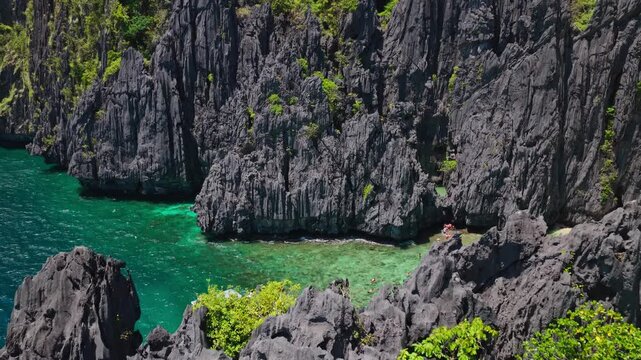 Dramatic Aerial Reveal of Limestone Cliffs Near Secret Lagoon in El Nido, Philippines. Cinematic Drone Flying Over Turquoise Ocean to Expose Towering Karst Rock Formations.