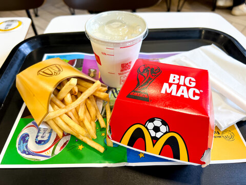 Close up view of a medium sized portion of McDonalds fries and a Big Mac hamburger in special World Cup packaging with banana milkshake for lunch