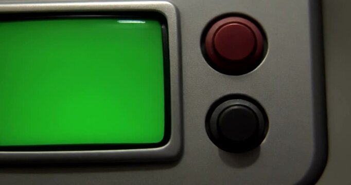 Close up of finger pressing red button on industrial machine with green screen display.