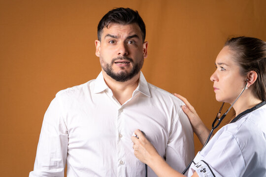 Doctora examinando la frecuencia card&iacute;aca de un paciente preocupado, usando su estetoscopio