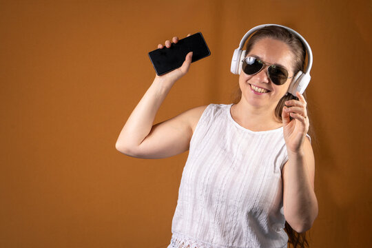 Mujer divirtiendose mucho escuchando m&uacute;sica usando sus auriculares bluetooth y su celular