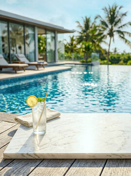 Empty marble podium with lemonade and folded napkin by a luxury infinity pool with sun loungers and tropical villa backdrop. Good for product display.