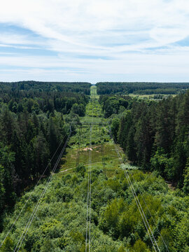 Aerial view of a power line corridor cutting through the dense forest of Gauja National Park in Incukalns, Sigulda Municipality, Latvia.