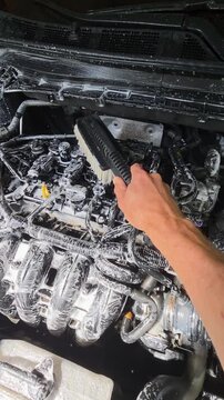 washing car engine bay with foam and brush
