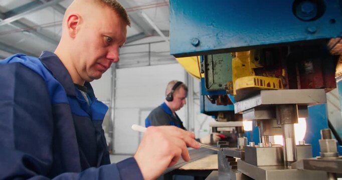 Skilled machine operators carrying out industrial fabrication tasks in a metal stamping facility