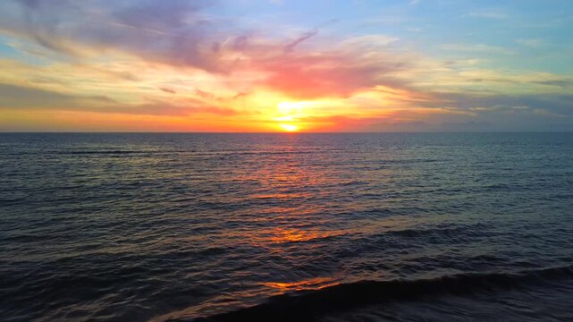 A breathtaking panoramic view of a dramatic golden sunset over the Mediterranean Sea in Agropoli, Cilento coast. The sky is filled with vibrant hues of orange, pink, yellow, and blue clouds, while the