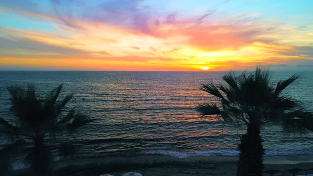 A breathtaking panoramic view of a dramatic golden sunset over the Mediterranean Sea in Agropoli, Cilento coast. The sky is filled with vibrant hues of orange, pink, yellow, and blue clouds, while the