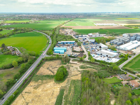 Interesting drop view of the Cambridgeshire, UK landscape showing a major road bypass connecting Peterborough to Cambridge. On the right is an industrial estate and grain storage facility.