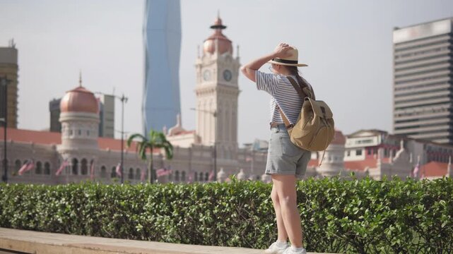 Female tourist in hat with backpack walking in Kuala Lumpur