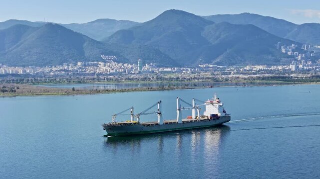 Commercial freight dry cargo ship bulker traveling across open bay water in daylight. Suitable for supply chain, cargo transport and international shipping