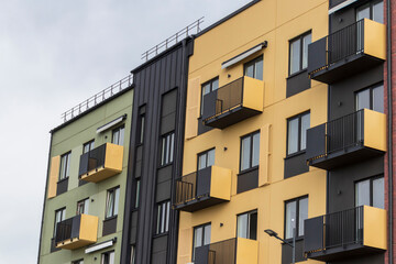 Fototapeta premium Modern residential building facade with geometric balconies, brick accent walls, and contemporary apartment block design. Urban