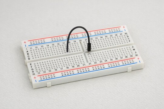 A simple white breadboard with red and blue stripes for identification or organization