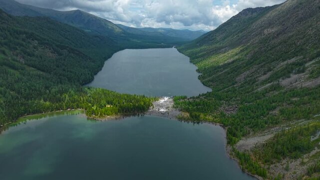 Epic aerial drone panorama showing the connection of Lower and Middle Multinskoe lakes with a white water river stream flowing through the moraine dam in Altai.