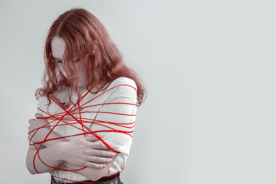 Teen girl tangled in red lines, concept of manipulation, pressure and judgment, personal boundaries violated, anxiety and avoiding conflict in social environment.