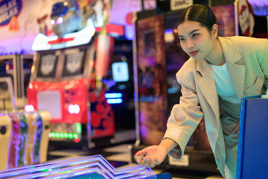 Young Thai Isan businesswoman playing a ball rolling game at an arcade center