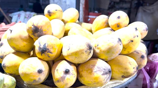 Fresh Mangoes for Sale: A vibrant display of ripe, yellow mangoes with dark spots, piled high for purchase at an outdoor market.