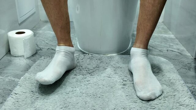 Close-up of the legs of a person sitting on a toilet