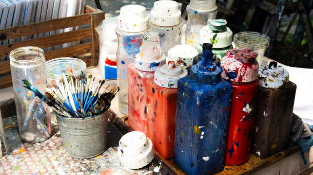 Artist messy workstation filled with colorful acrylic paint bottles and buckets of paintbrushes capturing fun weekend hobby workshop for thai people traveler join craft artisan in Nonthaburi, Thailand