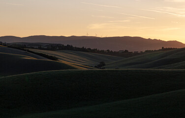 Fototapeta premium Tuscan Hills at Sunset with Wind Turbines and Cypress Trees, Italy