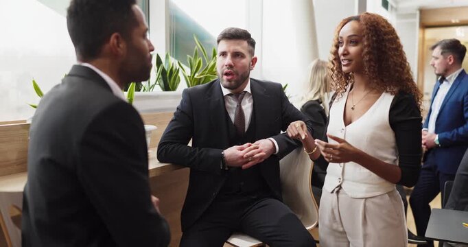 Business colleagues in office conversation during meeting. Professionals stand and talk by a window, smiling as other people network in the background. Strong teamwork and collaboration concept.