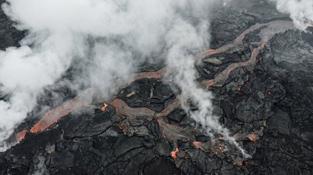 Aerial press view of active volcanic fissure with glowing magma channels beneath cracked basalt crust and dense white steam plumes