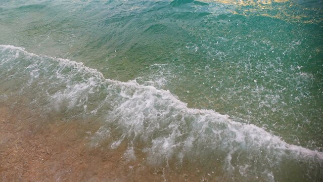 Turquoise sea surface with waves splash on the shore, ariel water splash background