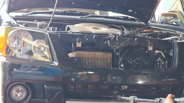 Professional auto mechanic calmly inspecting and servicing a vehicle air conditioning system in a modern, well-equipped auto repair garage.