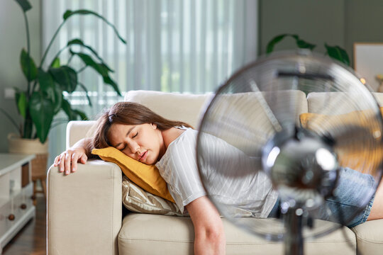 Exhausted woman sleeping in front of electric fan