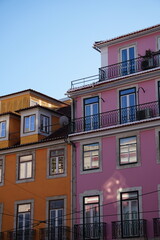 Fototapeta premium Colorful Orange and Pink Apartment Buildings with Iron Balconies Against Blue Sky, Lisbon, Portugal
