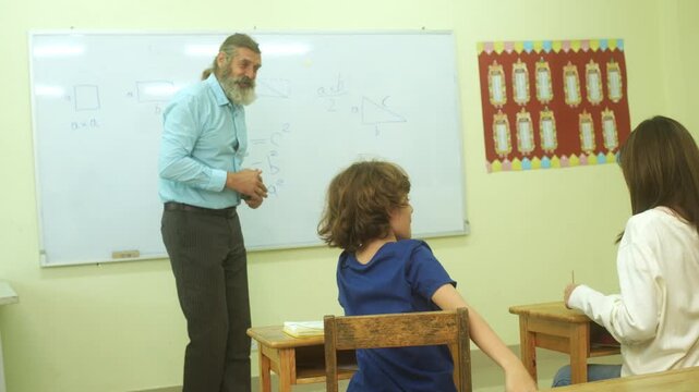 Multi-ethnic elementary school children assembling DIY robotic models during a STEM class with a senior teacher.