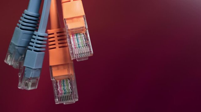 Four Ethernet network cables with different colorstwo blue and two orangeare prominently displayed against a gradient red background.
