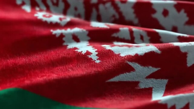 A close-up view of a waving flag, displaying a red backdrop with intricate white floral patterns