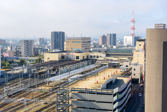 Elevated view of a train station surrounded by multi-storey car parks and apartment buildings in a city centre on a foggy autumn morrning