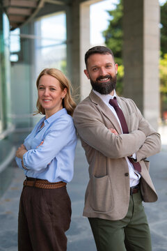 Business partners smiling back to back with crossed arms
