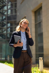 Fototapeta premium Businesswoman talking on phone walking in city