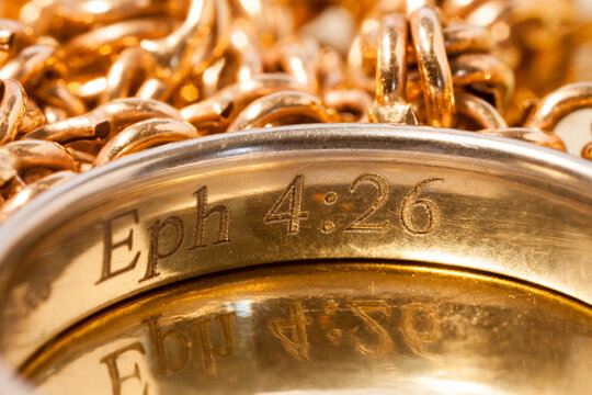 Gold ring engraved with Eph 4:26 and gold chain background